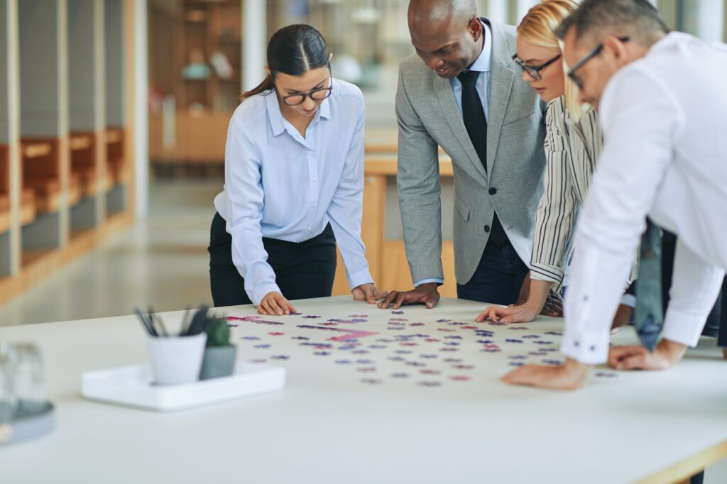 Diverse businesspeople solving a jigsaw puzzle together in an office