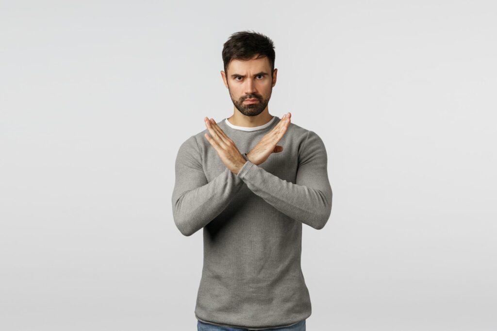 No, never accept it. Serious, confident bearded man in grey sweater, making cross stop gesture